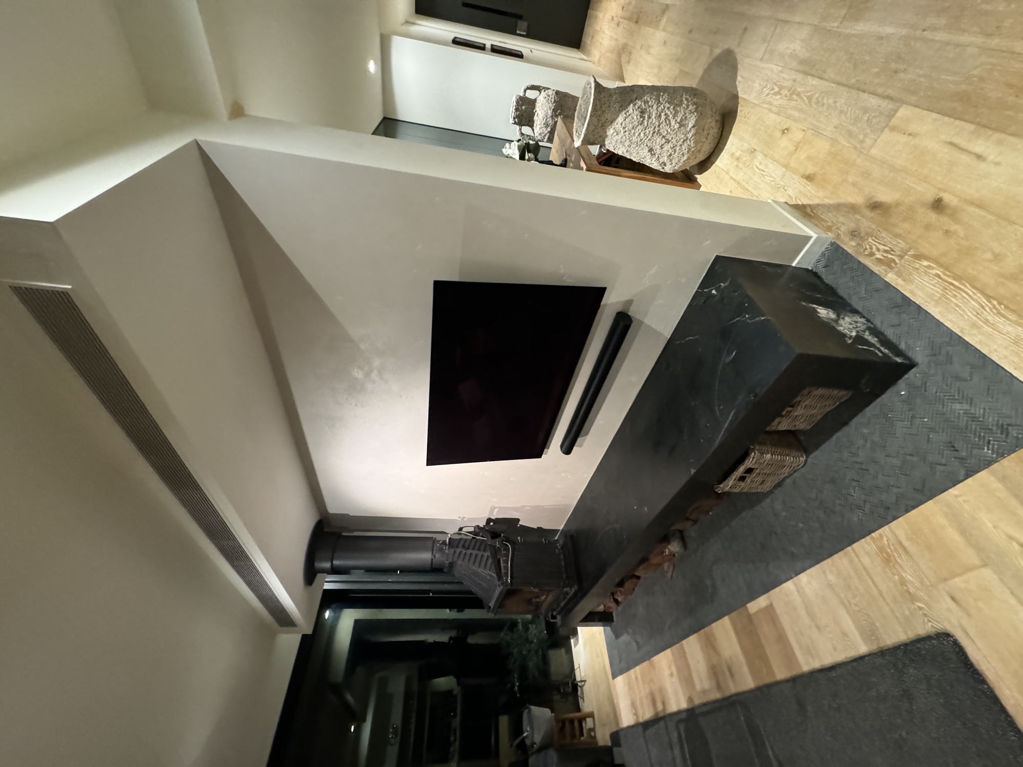Architectural fireplace with black stone plinth and freestanding wood heater