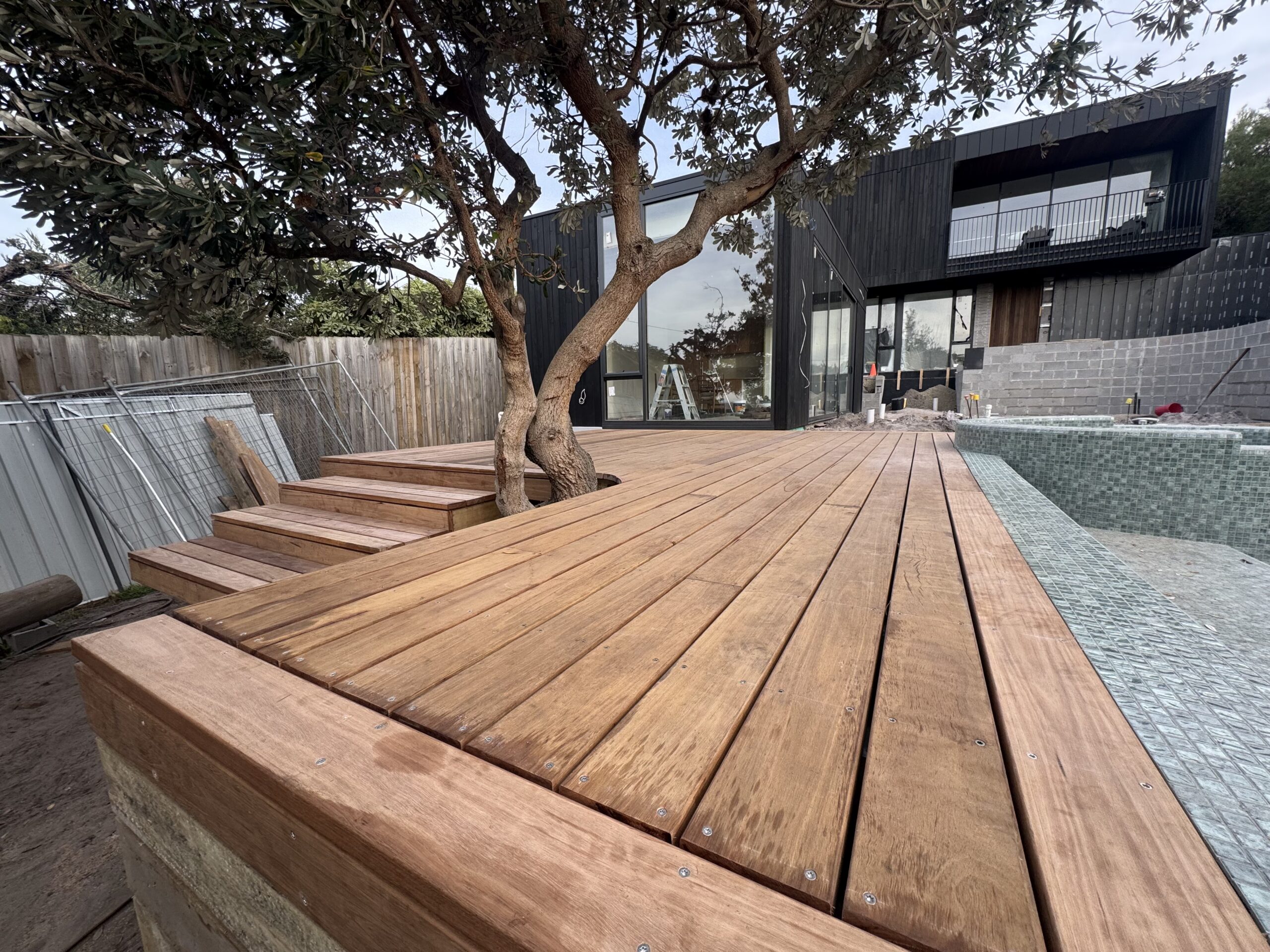 Hardwood deck with dark-clad coastal home and pool