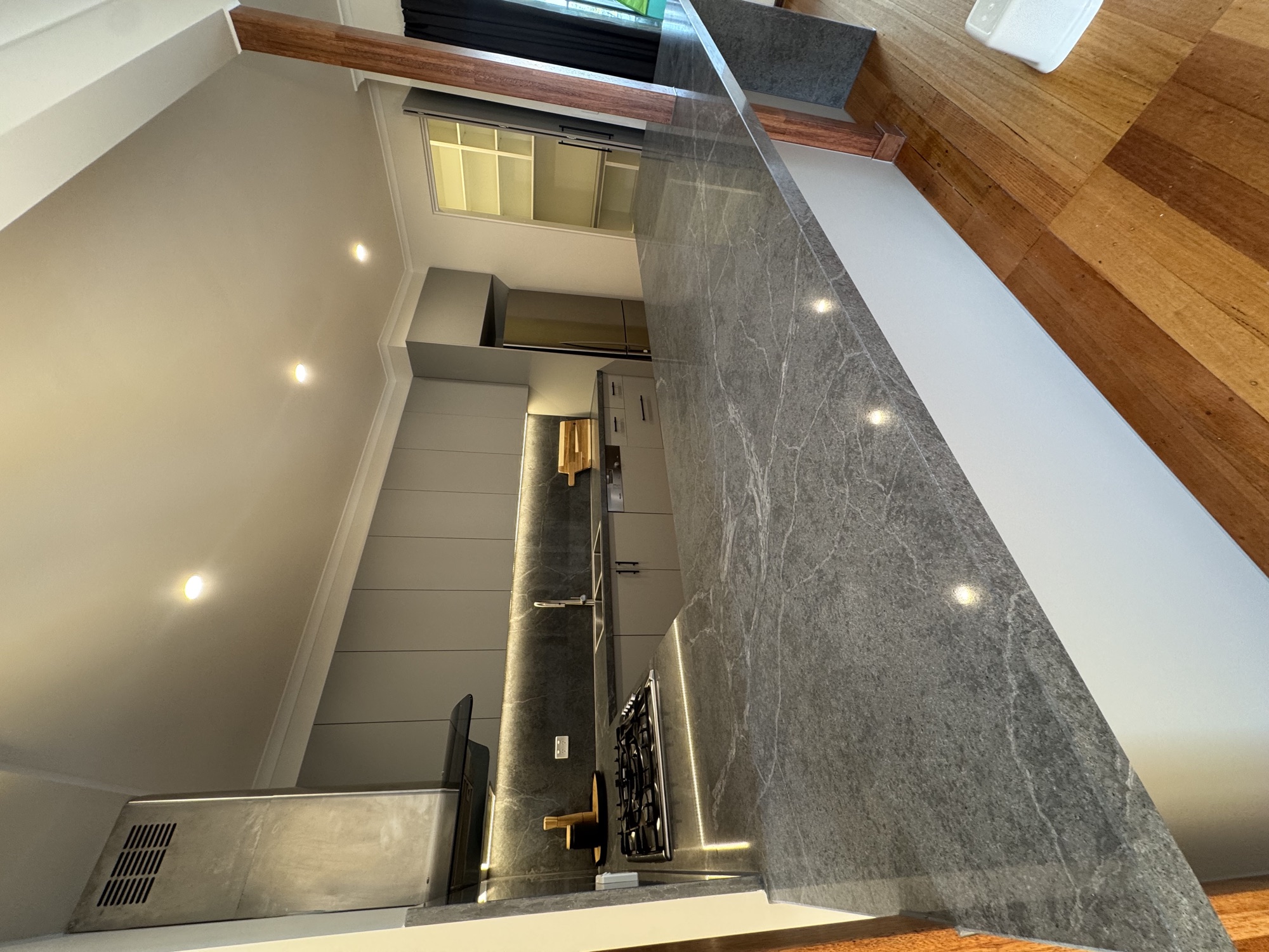 Grey cabinetry kitchen with veined stone benchtop and timber floor