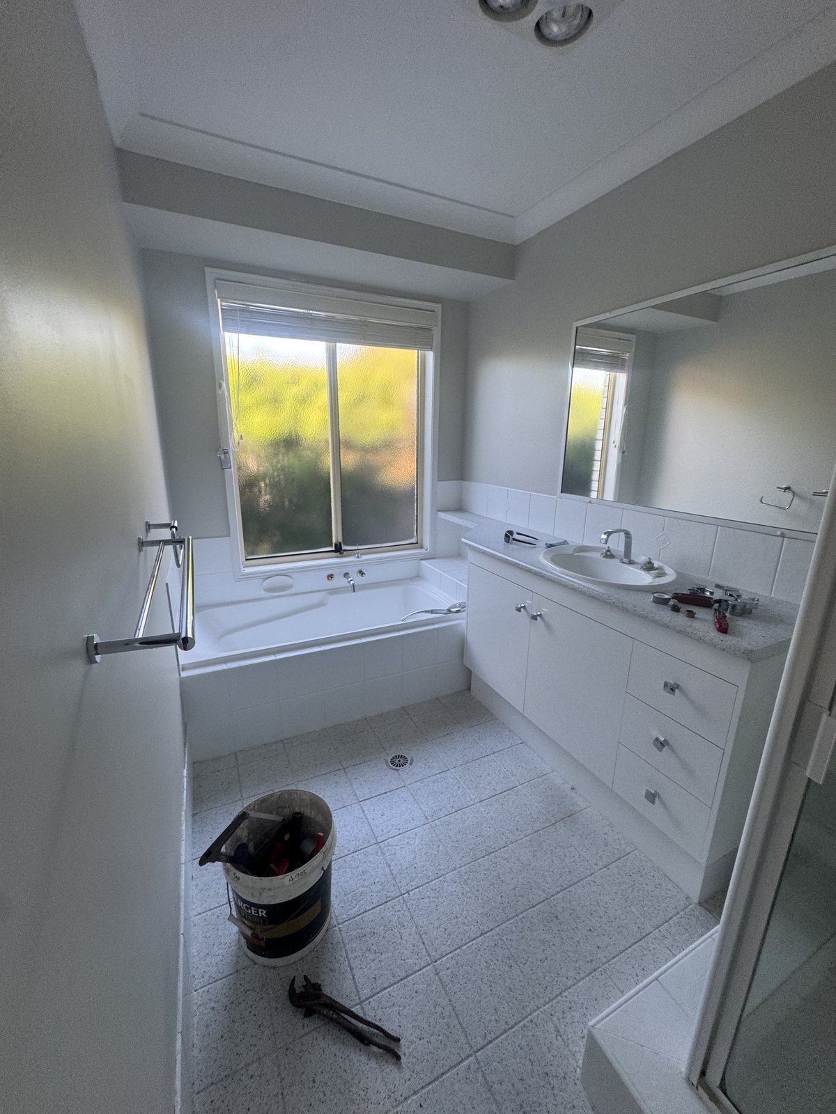The original main bathroom: bath under the window, dated vanity and speckled tile